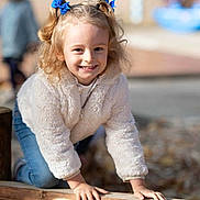 Mélodie participe au concours pour gagner de l'argent avec cette photo : child, girl, smile, blue_bows, curly_hair, outdoor, wooden_beam, playful, happy, casual_clothing, white_jacket, jeans, daylight, fun, childhood, portrait, young, cute, hands, nature