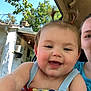 Annabelle is registered to the contest to win money with this photo: baby, child, smiling, pigtails, blue_dress, butterfly, face, person, happy, outdoor, car, window, tree, leaf, sky, adult, hand, clothing, portrait, sunlight