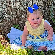 Annabelle joined the competition — help win amazing prizes! baby, child, blue_bow, yellow_dress, floral_pattern, sitting, blanket, tree_trunk, grass, outdoor, nature, cute, portrait, smiling, barefoot, greenery, sunlight, infant, young_child, face