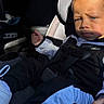 toddler, child, car_seat, curly_hair, blue_eyes, sportswear, seatbelt, car_interior, sunlight, shadow, serious_expression, clothing, footwear, young_child, portrait, baby, person, indoor, transportation, sitting