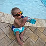 Rylee Rice is registered to the contest to win money with this photo: toddler, child, pool, water, sunglasses, bottle, swim_shorts, barefoot, wet_hair, sitting, outdoor, summer, reflection, drink, sidewalk, tiles, sunny, relaxation, young_child, fun