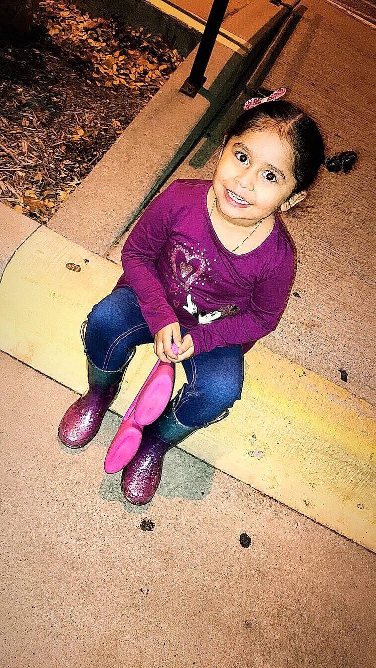 Irie is registered to the contest to win money with this photo: child, day, emotion, eye, facial_expression, footwear, fun, girl, human_body, joy, leg, person, pink, purple, red, shoe, sitting, skin, smile, standing