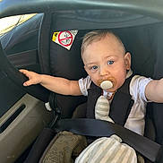 Harold participe au concours pour gagner de l'argent avec cette photo : baby, pacifier, car_seat, child, plush_toy, seatbelt, car_interior, blue_eyes, white_shirt, striped_toy, infant, child_safety, window, seat, casual_clothing, curious_expression, toddler, travel, car, baby_reaching