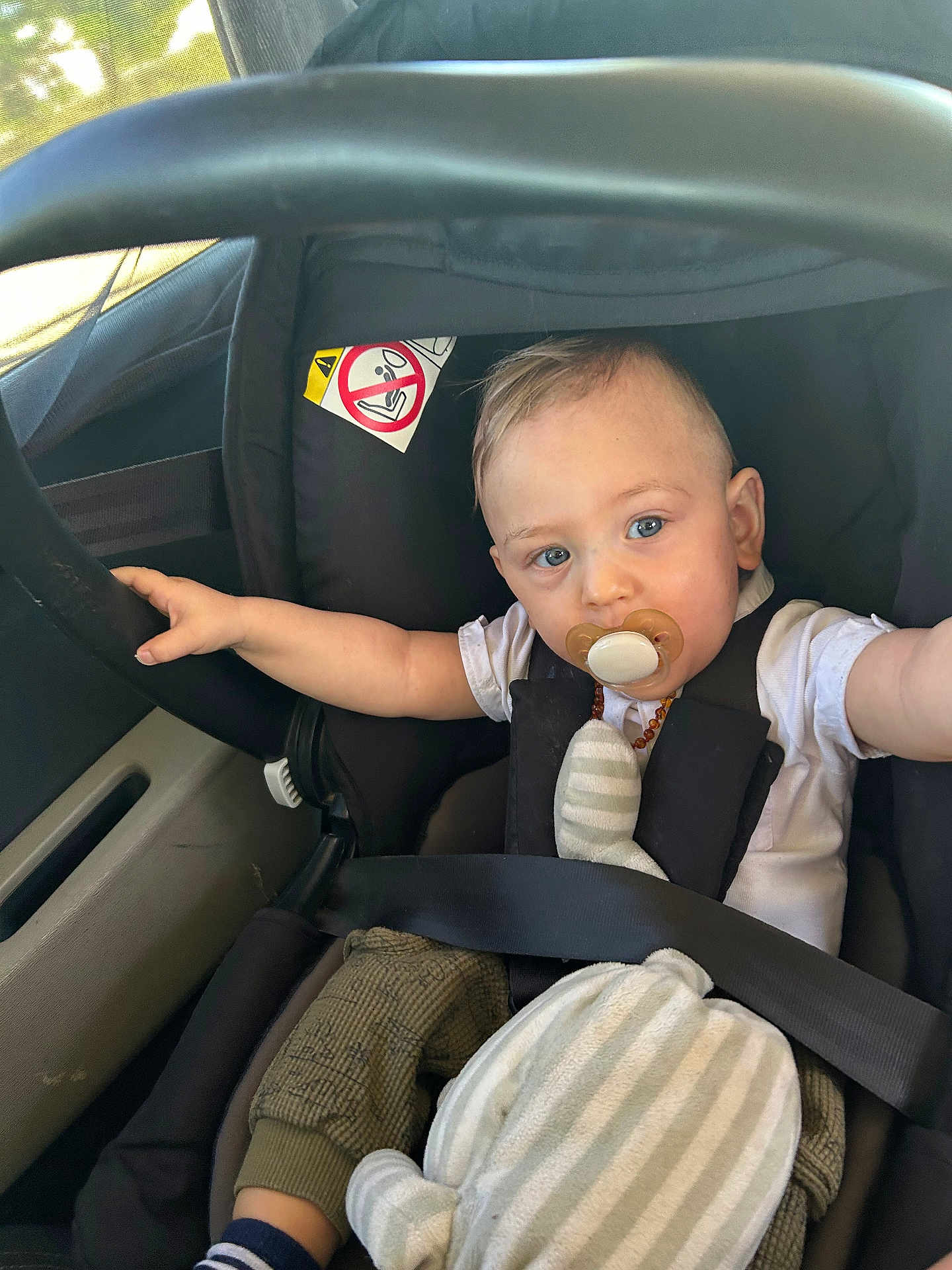 Harold participe au concours pour gagner de l'argent avec cette photo : baby, pacifier, car_seat, child, plush_toy, seatbelt, car_interior, blue_eyes, white_shirt, striped_toy, infant, child_safety, window, seat, casual_clothing, curious_expression, toddler, travel, car, baby_reaching