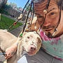 Noel O is registered to the contest to win money with this photo: man, dog, braids, beads, outdoor, sunlight, backyard, grass, fence, tattoo, casual_clothing, tie_dye, pet, companion, portrait, smile, friendship, leash, animal, human