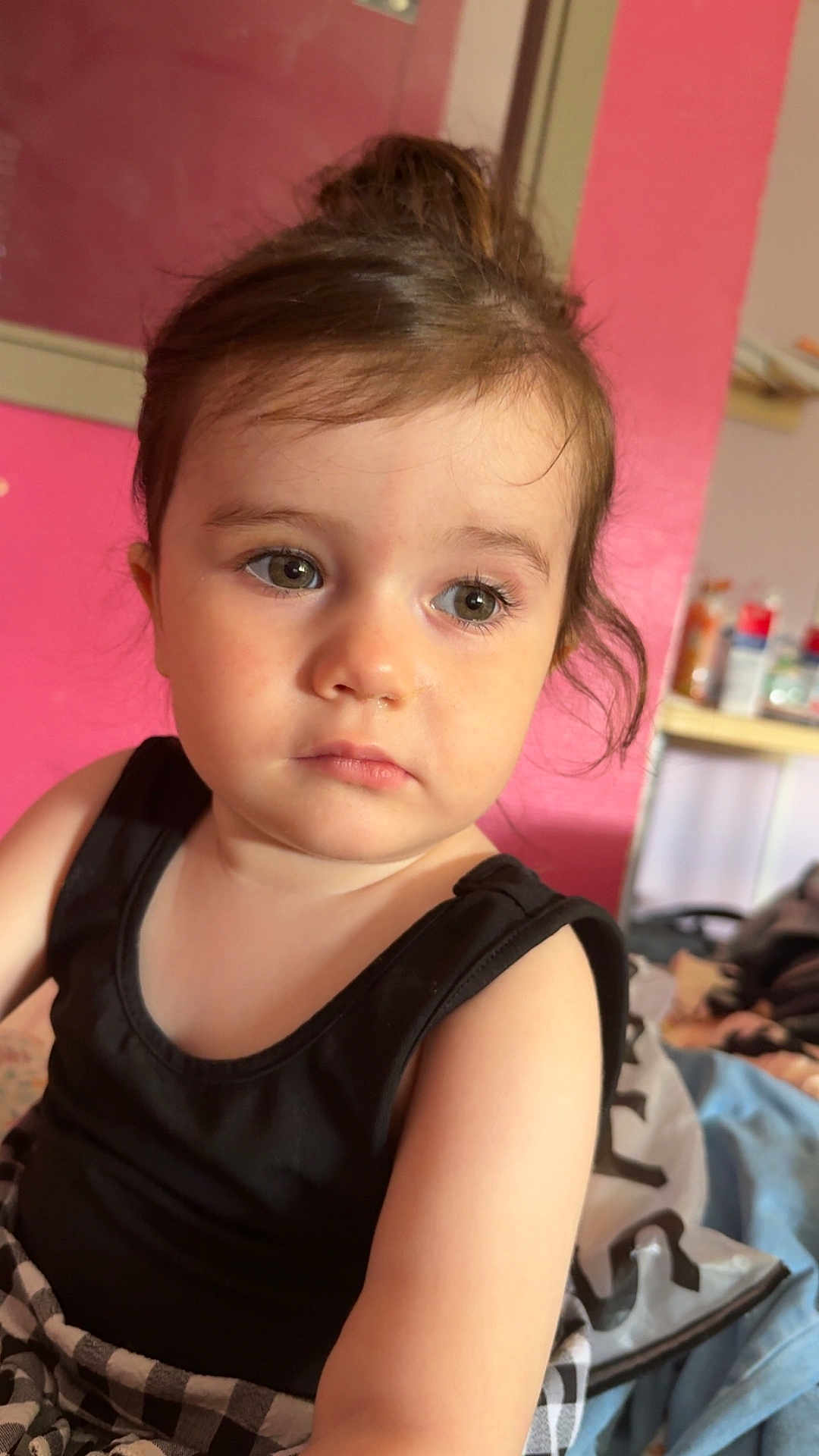 Tyanna a rejoint le concours — aidez-le/la à gagner de superbes lots ! toddler, child, face, portrait, black_tank_top, blanket, indoor, curly_hair, expression, looking_away, pink_wall, shelf, household_items, casual, young_child, skin, person, clothing, head, eyes
