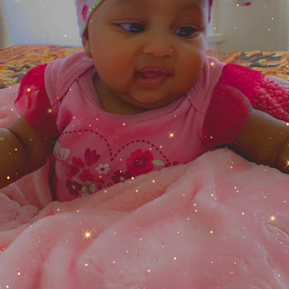 Laila is registered to the contest to win money with this photo: baby, child, infant, headwrap, pink_clothing, blanket, lying_down, face, smiling, indoors, soft_texture, cute, adorable, sparkles, cozy, portrait, happy, young_child, colorful, warm