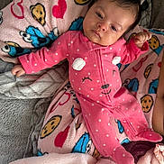 Imani joined the competition — help win amazing prizes! baby, infant, pink_onesie, polka_dots, blanket, cookie_pattern, heart_pattern, sleepy, cute, face, child, soft_texture, indoor, cozy, clothing, person, lying_down, comfort, warm, cute_expression