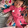baby, infant, pink_onesie, polka_dots, blanket, cookie_pattern, heart_pattern, sleepy, cute, face, child, soft_texture, indoor, cozy, clothing, person, lying_down, comfort, warm, cute_expression