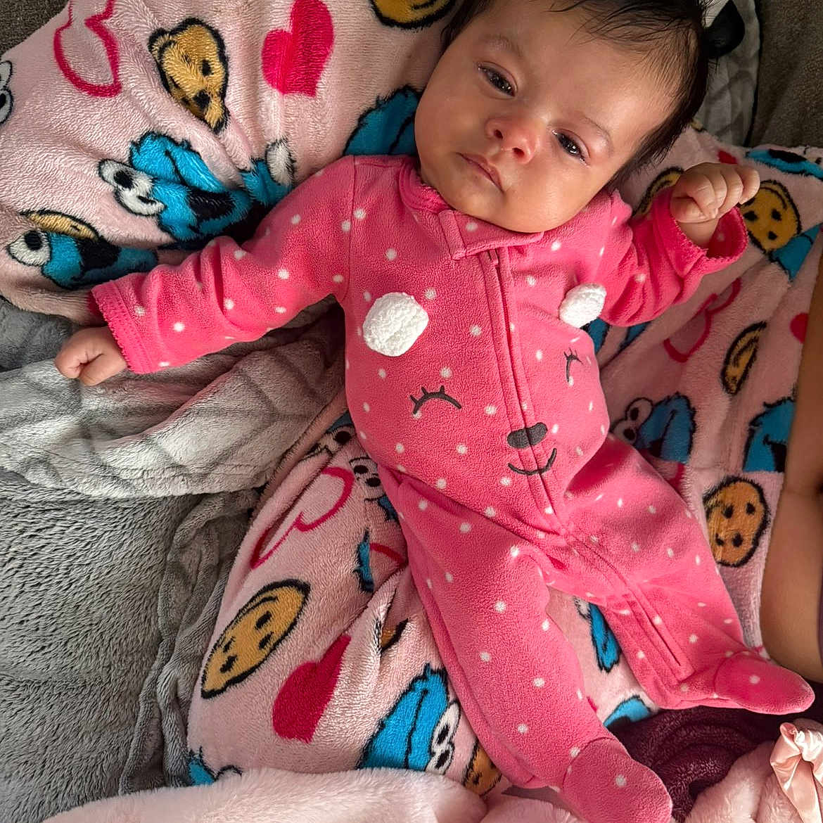 Imani joined the competition — help win amazing prizes! baby, infant, pink_onesie, polka_dots, blanket, cookie_pattern, heart_pattern, sleepy, cute, face, child, soft_texture, indoor, cozy, clothing, person, lying_down, comfort, warm, cute_expression