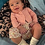 Delilah is registered to the contest to win money with this photo: baby, infant, smile, pink_cardigan, floral_print, blanket, leopard_pattern, socks, hands, legs, blue_sheet, pillow, close_up, face, happy, lying_down, bedroom, skin, eyes, portrait