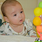 Axel joined the competition — help win amazing prizes! baby, infant, toy, colorful, curious, lying_down, indoor, child, face, eyes, clothing, soft_surface, playtime, expression, closeup, crawling, cute, attention, bright_colors, person