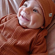 Tiago participe au concours pour gagner de l'argent avec cette photo : baby, infant, smile, dimples, orange_clothing, knit_hat, knitwear, cozy, cute, portrait, happy, child, face, closeup, soft_texture, blanket, indoor, young, person, warm