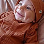 baby, infant, smile, dimples, orange_clothing, knit_hat, knitwear, cozy, cute, portrait, happy, child, face, closeup, soft_texture, blanket, indoor, young, person, warm