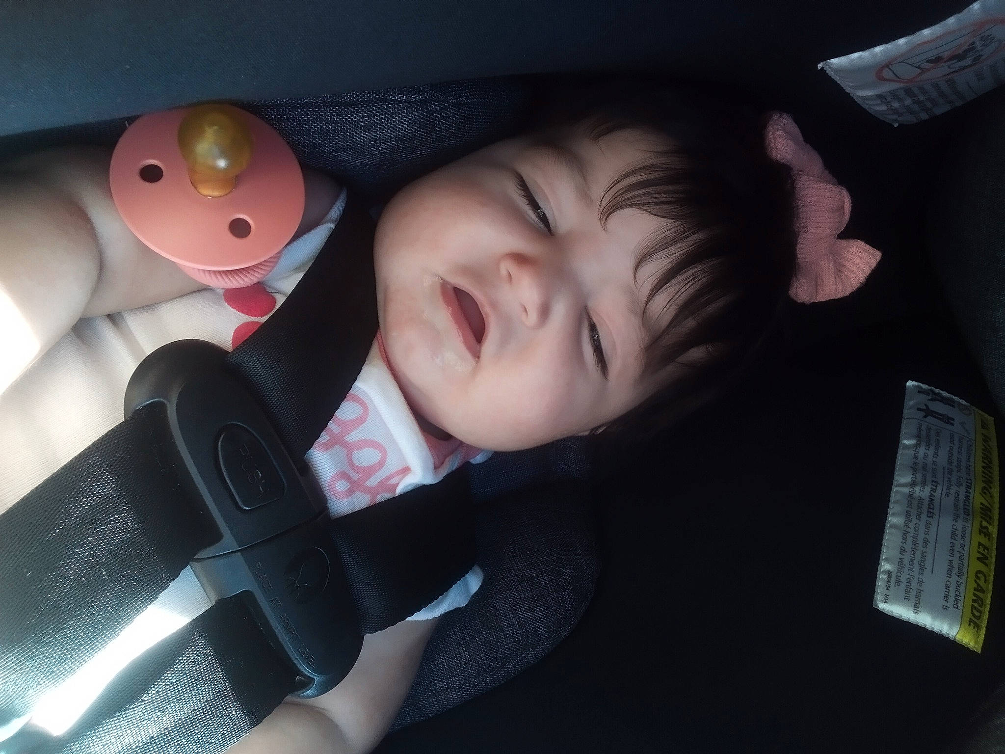 Alice is registered to the contest to win money with this photo: audio_equipment, baby, baby_products, baby_toddler_clothing, car_seat, carmine, cheek, child, comfort, finger, flash_photography, fun, nose, person, room, sitting, skin, smile, suit, toddler