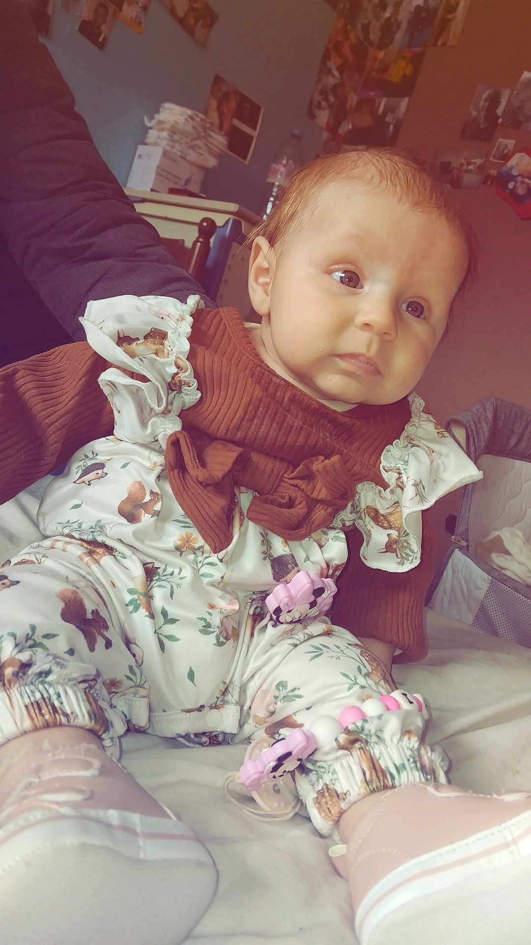 Inaya a rejoint le concours — aidez-le/la à gagner de superbes lots ! baby, child, infant, clothing, outfit, boots, bed, room, photographs, wall, person, sitting, curious, indoor, soft_lighting, cute, pink, brown, patterned, pacifier