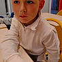 boy, casual_clothing, chair, child, classroom, desk, education, expression, furniture, hand, indoor, learning, pensive, person, school, seated, short_hair, white_sweater, yellow_chair, young