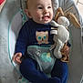 baby, infant, smiling, blue_clothing, plush_toy, baby_seat, cute, child, happy, indoor, floor_tiles, soft_toy, animal_print, cushion, person, portrait, one_person, young_child, small_hands, seated