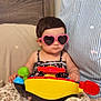 Sonia is registered to the contest to win money with this photo: baby, bed, blanket, child, cozy, cute, face, hands, heart_shaped, indoor, infant, leopard_print, pillow, pink, playful, seated, steering_wheel, striped, sunglasses, toy