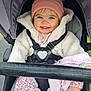 baby, child, smiling, stroller, hat, pink, jacket, coat, blue_eyes, happy, cute, outdoor, clothing, seatbelt, blanket, sock, person, infant, portrait, warm_clothes