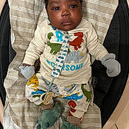 Kashton joined the competition — help win amazing prizes! baby, child, infant, face, mittens, dinosaur, clothing, blanket, footwear, slippers, pacifier, striped, pattern, cute, indoors, person, apparel, laying_down, expression, closeup
