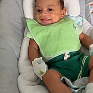 Noah joined the competition — help win amazing prizes! baby, child, infant, smiling, happy, portrait, face, eyes, indoors, bouncer, baby_seat, cushion, bib, green_clothing, shorts, socks, nursery, seated, relaxed, photography