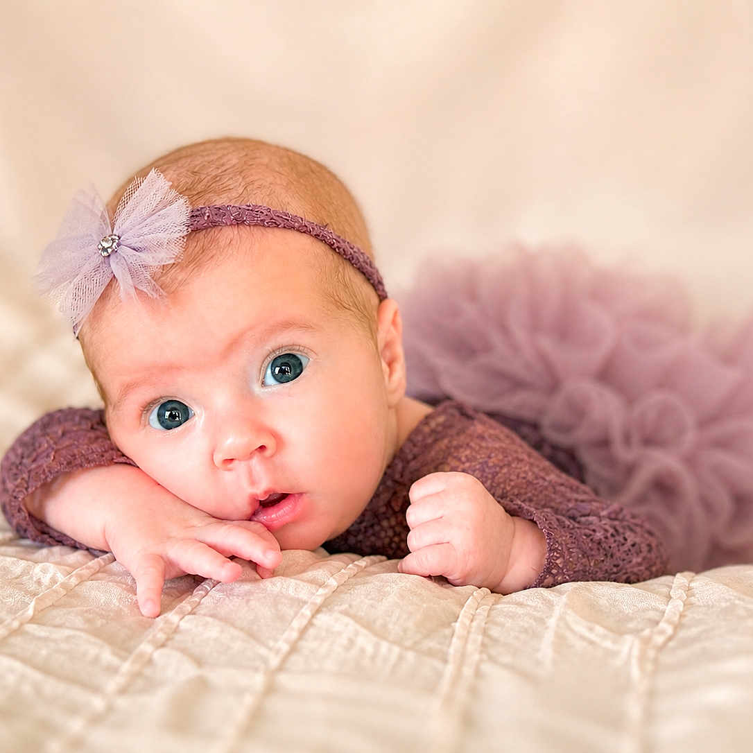 Maliah joined the competition — help win amazing prizes! baby, infant, face, headband, purple_clothing, tulle, blanket, bed, cute, portrait, newborn, sleepwear, hand, skin, eyes, expression, soft_light, indoor, child, resting