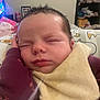 Emery is registered to the contest to win money with this photo: baby, sleeping, bib, hand, face, maroon_clothing, indoor, furniture, blanket, head, peaceful, child, person, portrait, resting, cozy, home, shelf, television, clutter