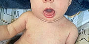 Emery is registered to the contest to win money with this photo: baby, infant, child, face, eyes, mouth, diaper, blanket, cushion, pattern, animal_print, skin, expression, indoors, person, cute, young, comfort, soft, sitting