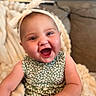 baby, baby_photography, blanket, bow, child, couch, cozy, eyes, face, green_clothing, happy, headband, indoor, infant, laughing, open_mouth, patterned_outfit, portrait, sitting, smiling