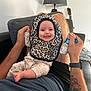Celeste a rejoint le concours — aidez-le/la à gagner de superbes lots ! baby, smiling, bib, leopard_print, adult, tattoo, couch, lamp, guitar, living_room, holding_hands, happy, sitting, clothing, person, furniture, casual, indoor, foot, watch