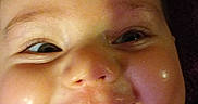 Alice is registered to the contest to win money with this photo: baby, button, cheeks, child, close_up, clothing, cute, expression, face, happy, head, indoors, infant, person, polka_dot, portrait, purple, skin, smiling, tongue_out