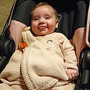 Alice is registered to the contest to win money with this photo: baby, smiling, tongue_out, stroller, indoor, cozy, clothing, blanket, carpet, boots, child, cute, person, infant, seat, happy, portrait, warm, comfortable, casual