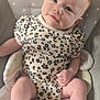 baby, infant, child, onesie, clothing, pattern, floral_pattern, polka_dot, blanket, cushion, seat, soft, cute, face, head, skin, expression, lying_down, indoors, relaxed