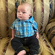 Sammy joined the competition — help win amazing prizes! baby, child, infant, plaid_shirt, blue_shirt, black_pants, barefoot, sofa, upholstery, patterned_fabric, seated, indoor, person, cute, young, portrait, furniture, home, expression, serious