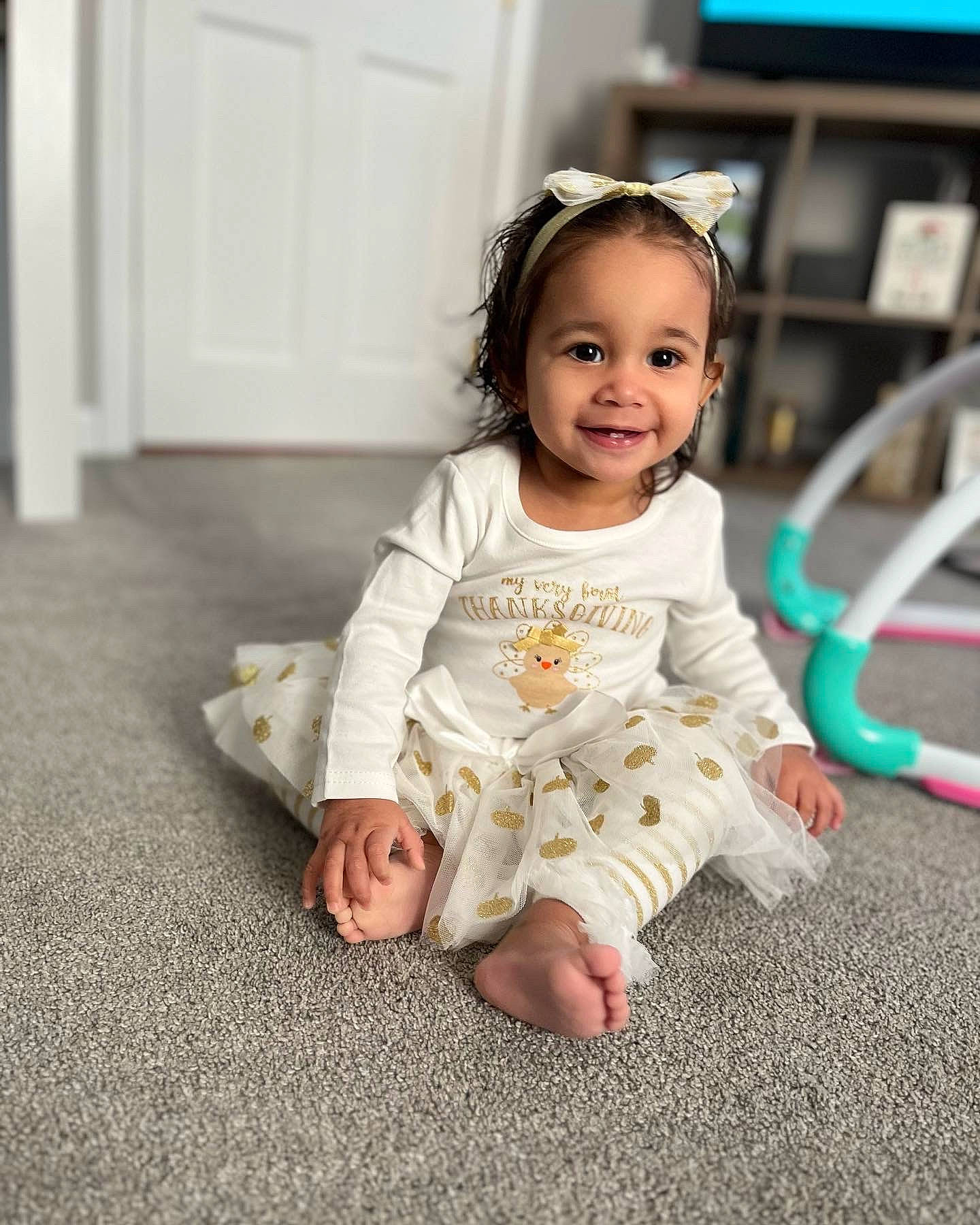 Isabella is registered to the contest to win money with this photo: baby, baby_toddler_clothing, cheek, child, door, face, flash_photography, floor, flooring, foot, fun, happy, head, iris, joy, person, sitting, skin, sleeve, smile