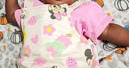 Desja King is registered to the contest to win money with this photo: baby, infant, child, blanket, pumpkin, pattern, pink_clothing, cartoon_characters, cute, smiling, face, hand, curly_hair, lying_down, soft_texture, indoors, portrait, happy, toddler, playful