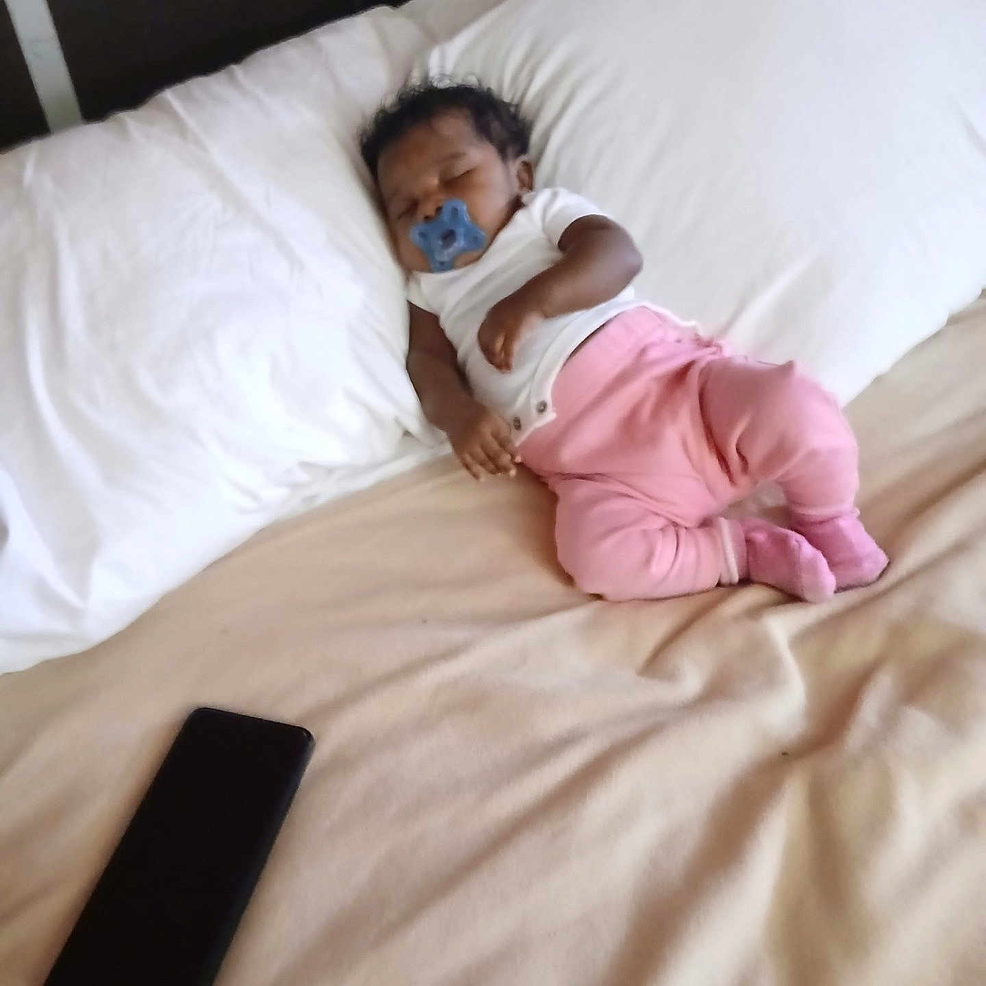 Desja King joined the competition — help win amazing prizes! baby, sleeping, pacifier, bed, pillow, pink_pants, white_shirt, smartphone, indoor, resting, infant, blanket, soft, child, cute, peaceful, lying_down, relaxation, home, cozy