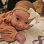 Adelaide is registered to the contest to win money with this photo: baby, infant, headband, bow, blanket, clothing, face, skin, hand, lying_down, indoors, cute, young_child, portrait, soft_texture, expression, person, newborn, closeup, gaze