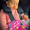 baby, child, car_seat, sleeping, pink_hoodie, plush_toy, owl_toy, seatbelt, pigtails, cute, peaceful, indoors, transportation, infant, portrait, clothing, small_hands, soft_lighting, toddler, resting