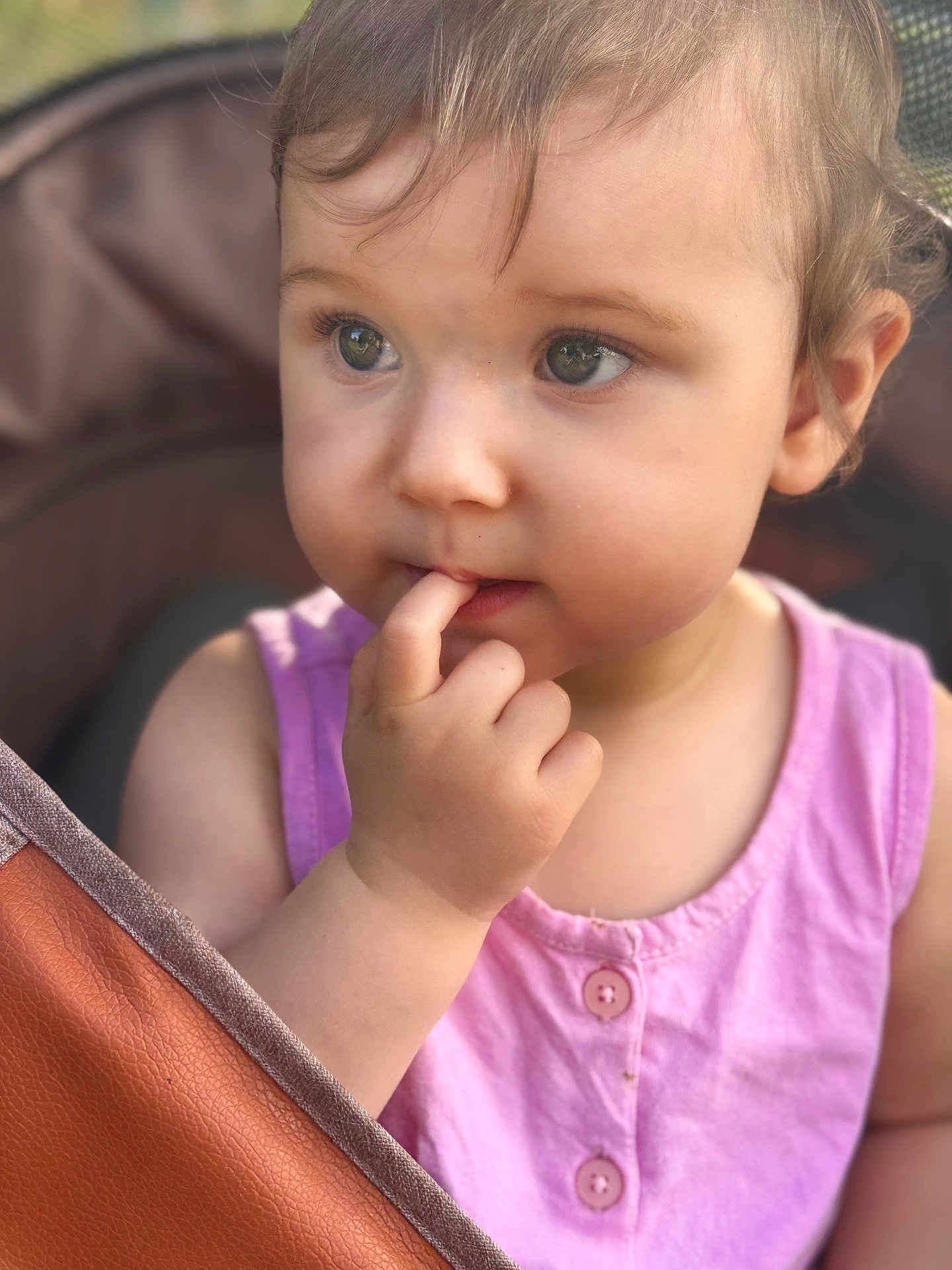 Romy participe au concours pour gagner de l'argent avec cette photo : toddler, child, face, finger, pink_clothing, curious, portrait, closeup, baby, cute, expression, skin, hair, eyes, hand, seat, stroller, outdoor, soft_light, casual