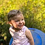 Romy a rejoint le concours — aidez-le/la à gagner de superbes lots ! toddler, child, smiling, outdoor, sunlight, greenery, blue_surface, happy, cute, baby, portrait, person, skin, hair, hand, tattoo, nature, blurred_background, sitting, casual_clothing