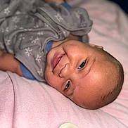 Zakhari is registered to the contest to win money with this photo: baby, smiling, infant, blanket, sleepwear, face, head, cheeks, eyes, person, cute, lying_down, cozy, soft, skin, indoors, portrait, happy, apparel, child