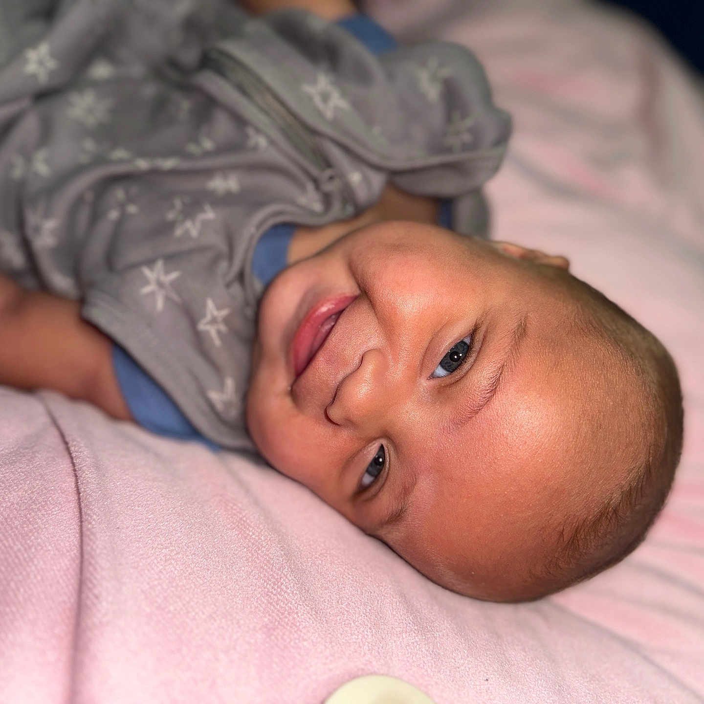 Zakhari is registered to the contest to win money with this photo: apparel, baby, blanket, cheeks, child, cozy, cute, eyes, face, happy, head, indoors, infant, lying_down, person, portrait, skin, sleepwear, smiling, soft