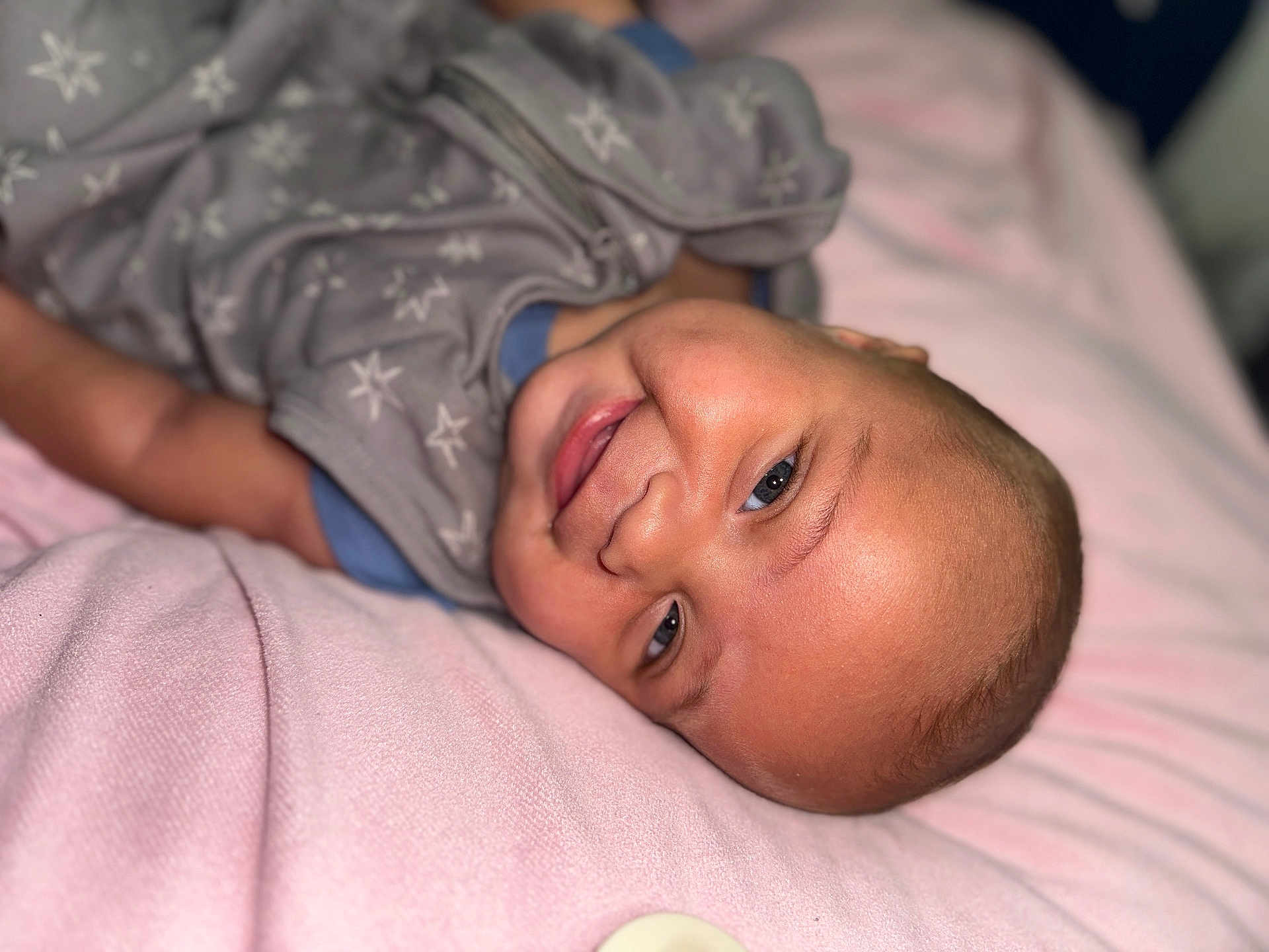 Zakhari is registered to the contest to win money with this photo: baby, smiling, infant, blanket, sleepwear, face, head, cheeks, eyes, person, cute, lying_down, cozy, soft, skin, indoors, portrait, happy, apparel, child