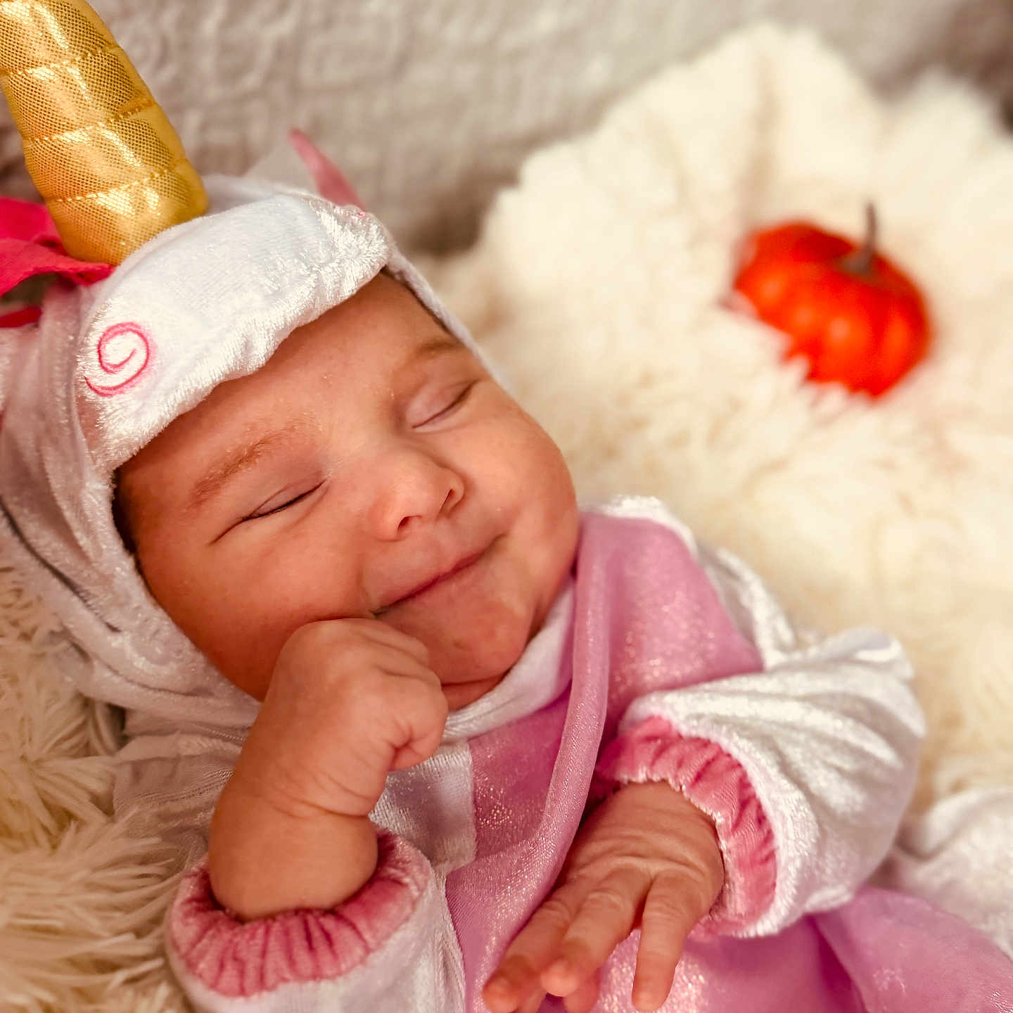 Sayda is registered to the contest to win money with this photo: baby, child, closed_eyes, costume, cozy, cute, cute_outfit, fluffy_blanket, hand, horn, indoors, infant, orange, pink_clothing, portrait, pumpkin, sleeping, smiling, soft_texture, unicorn_costume