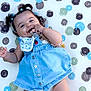 baby, child, infant, smiling, happy, pigtails, blue_dress, polka_dot, toy, beads, playmat, outdoor, grass, cute, chewing, barefoot, lying_down, accessory, white_bib, buttoned_dress