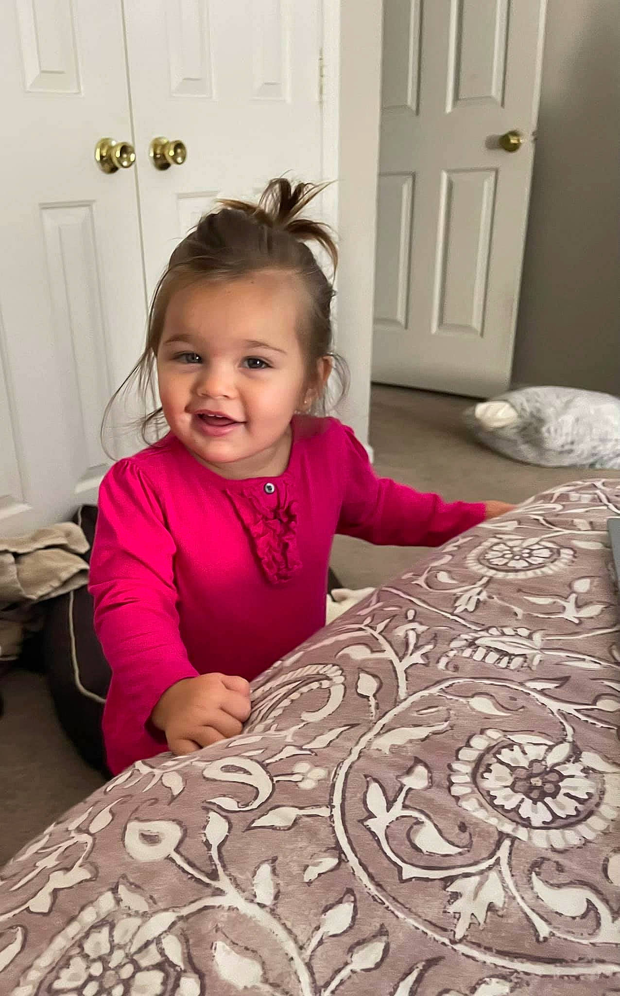 Mialina is registered to the contest to win money with this photo: baby_toddler_clothing, bed_sheet, bedding, child, door, facial_expression, flooring, fun, happy, home_door, joy, linens, magenta, pattern, person, purple, room, sitting, sleeve, smile
