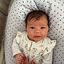 baby, infant, face, hand, pillow, pattern, stars, clothing, floral, cute, newborn, person, skin, hair, sleeping_area, bed, comfort, soft, tender, family