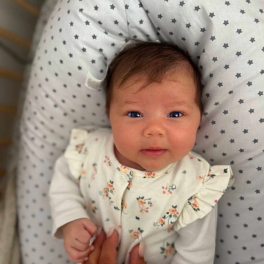 Giulia participe au concours pour gagner de l'argent avec cette photo : baby, bed, clothing, comfort, cute, face, family, floral, hair, hand, infant, newborn, pattern, person, pillow, skin, sleeping_area, soft, stars, tender